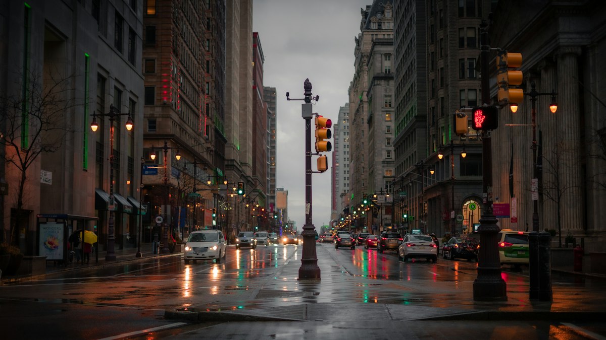 A downtown street with traffic signals and cars on a rainy day